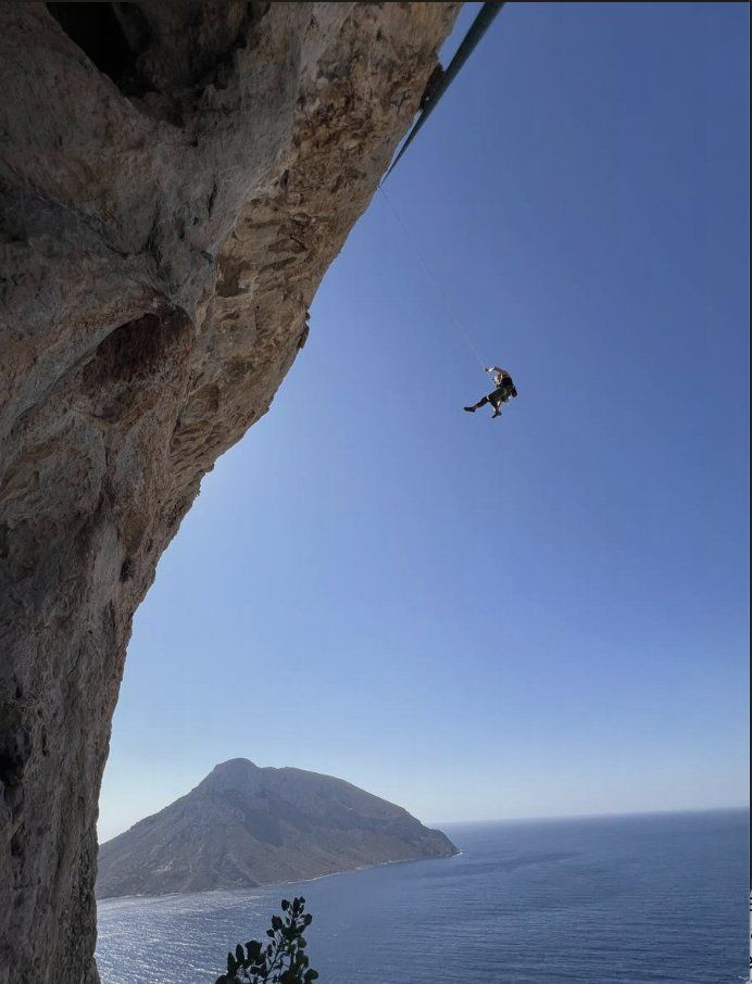 Sarabeth suspended on overhang above the sea