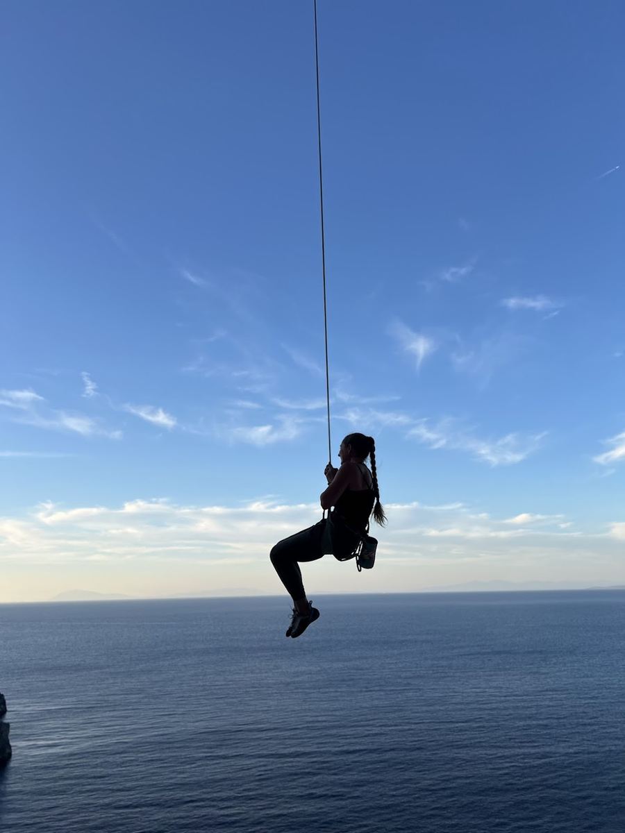 Sarabeth hanging on rope over the ocean